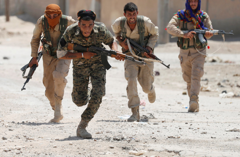 Kurdish fighters from the People's Protection Units (YPG) run from ISIS gunmen in Raqqa, Syria, July 3, 2017. (credit: REUTERS/GORAN TOMASEVIC/FILE PHOTO)