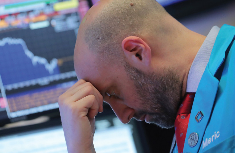 A trader works on the floor of the New York Stock Exchange in early December (photo credit: BRENDAN MCDERMID/REUTERS)