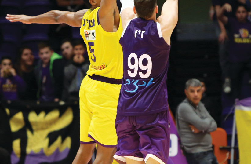 HAPOEL HOLON forward Darion Atkins (left) blocks a shot by Ironi Nahariya’s Yiftach Ziv during first-place Holon’s 78-72 victory on Wednesday night in BSL action (photo credit: UDI ZITIAT)