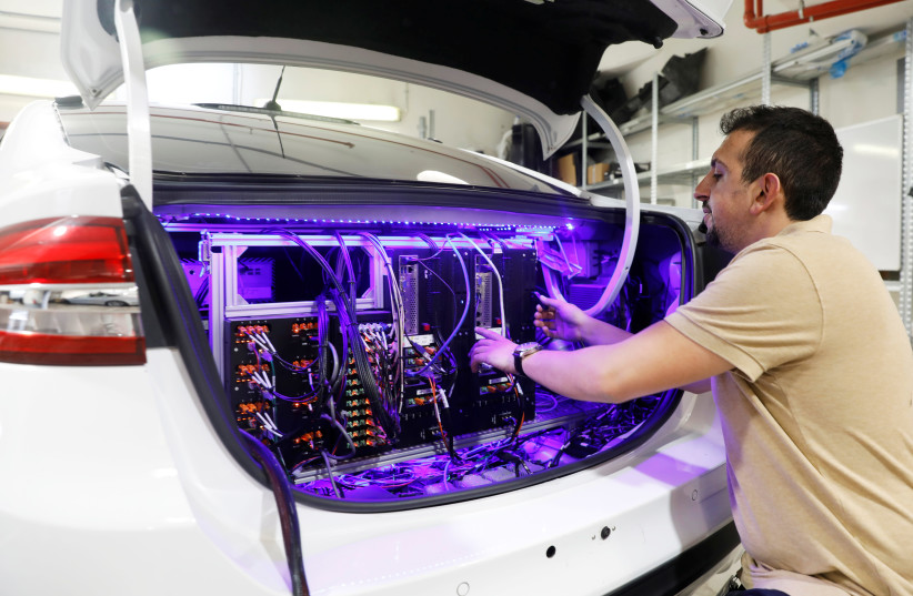 A worker tends to systems in the back of a Mobileye autonomous driving test vehicle, at the Mobileye headquarters in Jerusalem, May 15, 2018 (photo credit: RONEN ZVULUN/REUTERS)