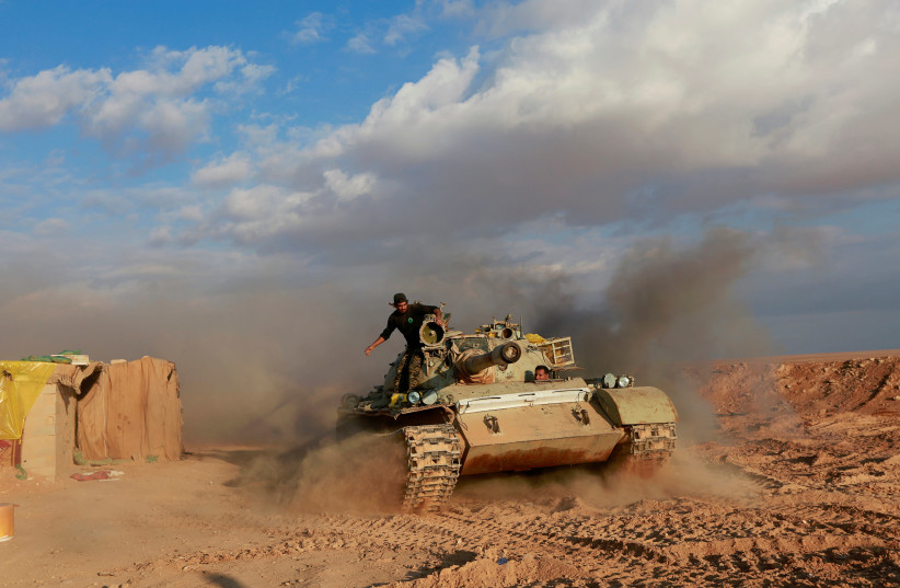 Iranian-backed militias stand on a tank close to the Syria-Iraq border (credit: ALAA AL-MARJANI/REUTERS)