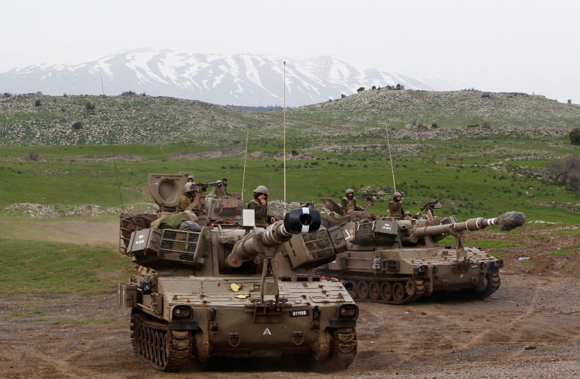 Mount Hermon is seen in the background as Israeli soldiers travel on mobile artillery units after an exercise in the Golan Heights, February 2013 (photo credit: BAZ RATNER/REUTERS)
