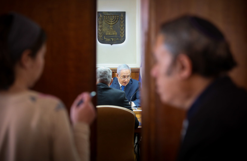 Prime Minister Benjamin Netanyahu is seen through an open door as he convenes a recent cabinet meeting (photo credit: MARC ISRAEL SELLEM/WIKIMEDIA COMMONS)