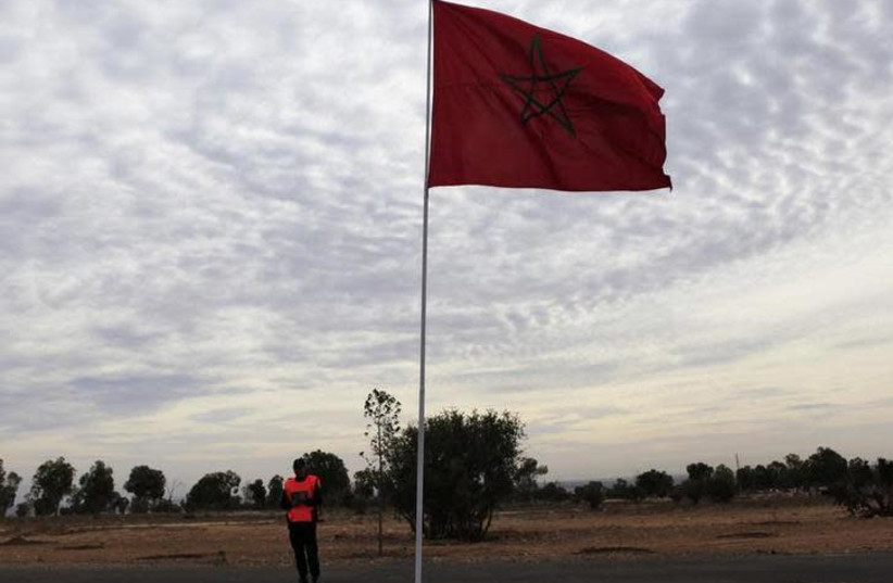 A police officer stands near a Moroccan national flag (photo credit: REUTERS/AMR ABDALLAH DALSH)