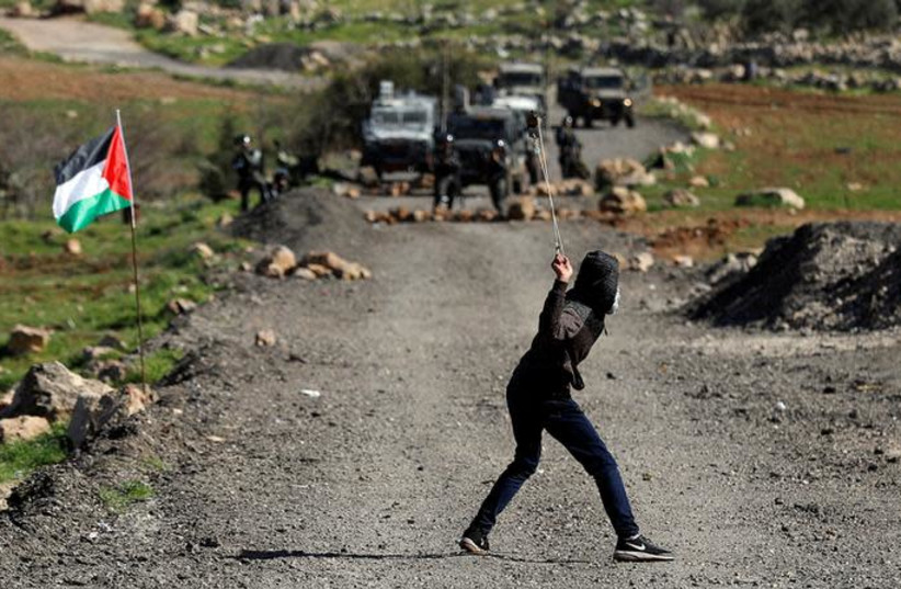 A Palestinian demonstrator uses a sling to hurl stones at Israeli troops during clashes at a protest in al-Mughayyir village near Ramallah (photo credit: REUTERS/MOHAMAD TOROKMAN)