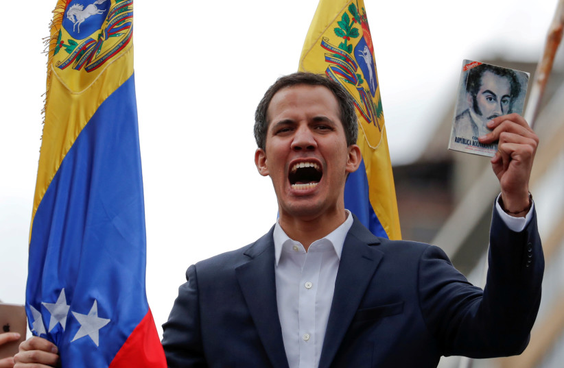 Juan Guaido, President of Venezuela's National Assembly, holds a copy of Venezuelan constitution during a rally against Venezuelan President Nicolas Maduro's government and to commemorate the 61st anniversary of the end of the dictatorship of Marcos Perez Jimenez in Caracas, Venezuela January 23, 20 (photo credit: CARLOS GARCIA RAWLINS/ REUTERS)