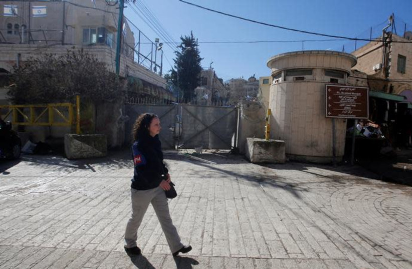 A member of the Temporary International Presence in Hebron (TIPH) walks past the Beit Romano settlement in Hebron, in the West Bank January 29, 2019 (photo credit: REUTERS/MUSSA QAWASMA)