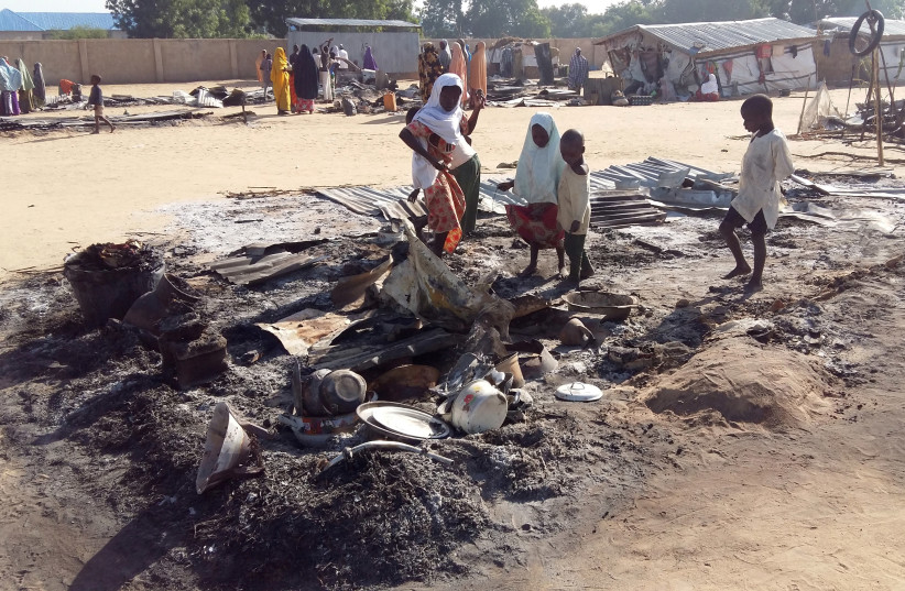 FILE PHOTO: People stand amid the damage at a camp for displaced people after an attack by suspected Boko Haram insurgents in Dalori, Nigeria November 1, 2018 (photo credit: KOLAWOLE ADEWALE / REUTERS)