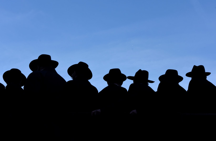Rabbis hats are silhouetted against the sky as they gather to pose for a group photo in front of the Chabad-Lubavitch world headquarters in the Brooklyn borough of New York, U.S., November 4, 2018. (photo credit: MARK KAUZLARICH/REUTERS)
