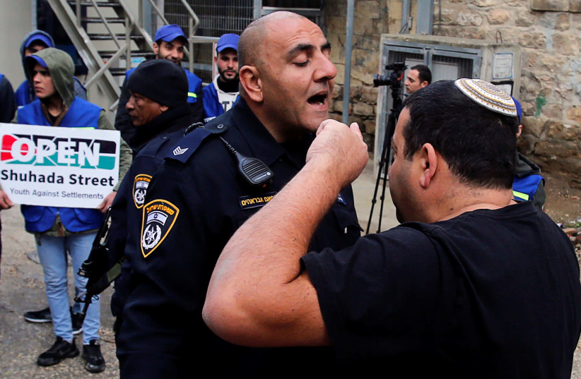 A Jewish settler argues with an Israeli policeman during a protest by Palestinians in Hebron February 10, 2019 (photo credit: REUTERS/MUSSA QAWASMA)
