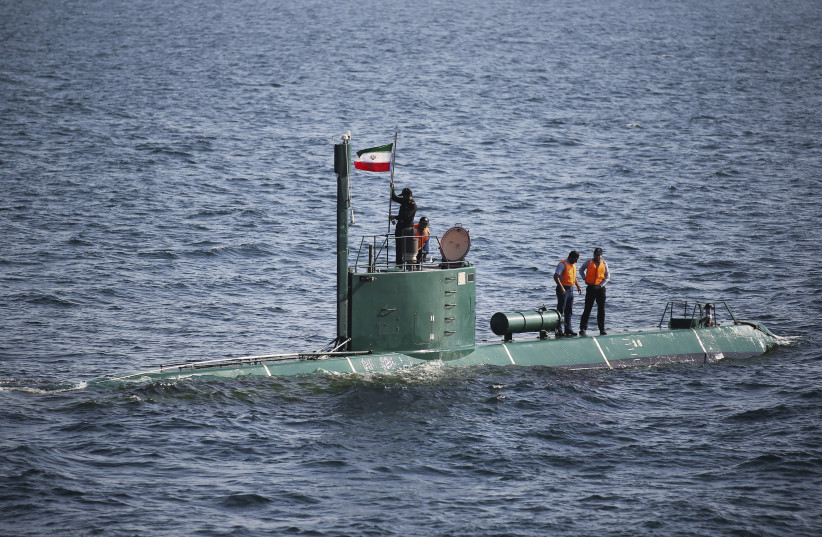 Military personnel place a flag on a submarine during the Velayat-90 war games by the Iranian navy in the Strait of Hormuz (photo credit: ALI MOHAMMAD/REUTERS/IIPA)