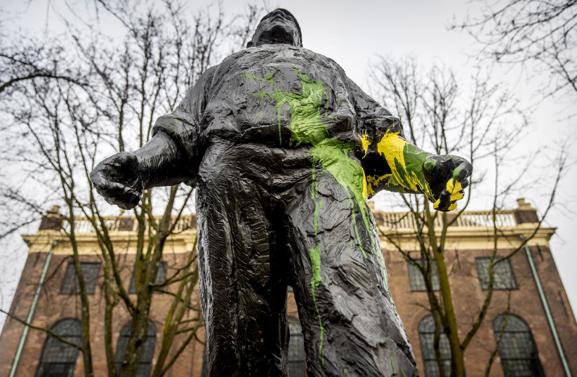 This picture taken on February 22, 2019 shows the statue of De dokwerker (the docker), in memory of a strike against the German occupation during WWII, in Amsterdam, covered with yellow and green paint by supporters of club ADO The Hague prior to the premier league football match against Ajax that w (photo credit: KOEN VAN WEEL / ANP / AFP)