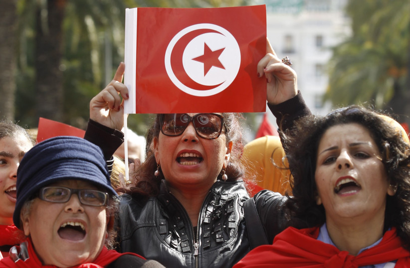 A Tunisian woman holds up a flag during a march to celebrate International Women's Day in Tunis March 8, 2014. (photo credit: ZOUBEIR SOUISSI / REUTERS)