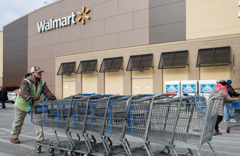 An employee pushes shopping carts outside a Walmart store in Chicago, Illinois, U.S., November 20, 2018 (credit: KAMIL KRACZYNSKI/ REUTERS)