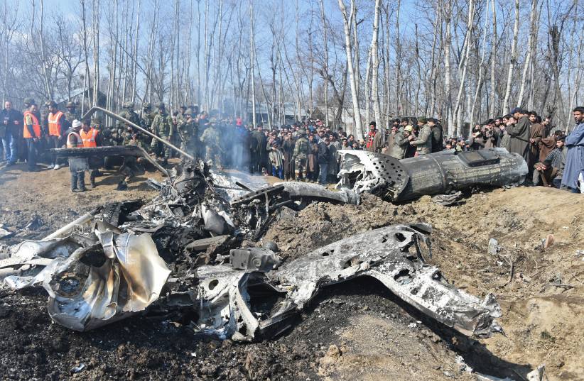 Indian soldiers and Kashmiri onlookers stand near the remains of an Indian Air Force aircraft after it crashed in Budgam district, some 30 kms from Srinagar on February 27, 2019 (photo credit: TAUSEEF MUSTAFA/AFP)