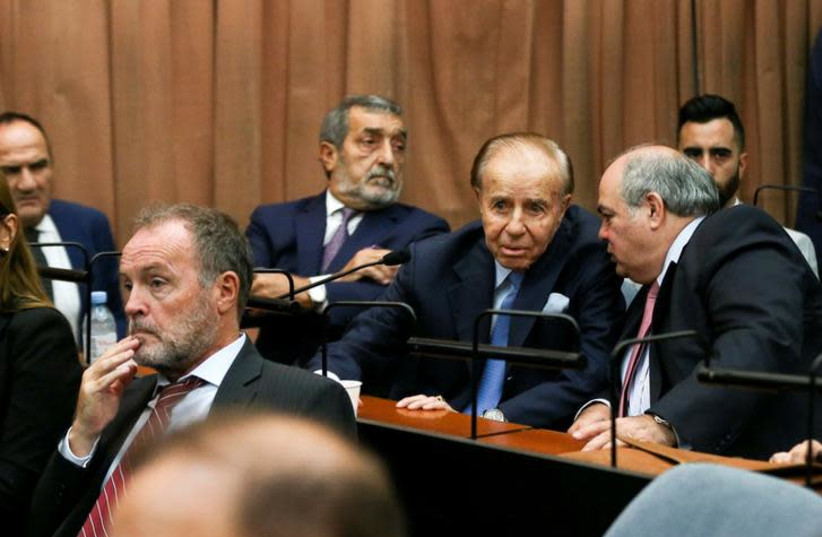 Former Argentine President Carlos Menem talks to an unidentified man behind former prosecutor Eamon Mullen in a court room before hearing the verdict in the trial of covering up the 1994 AMIA bombing, in Buenos Aires, Argentina. February 28, 2019 (photo credit: REUTERS)