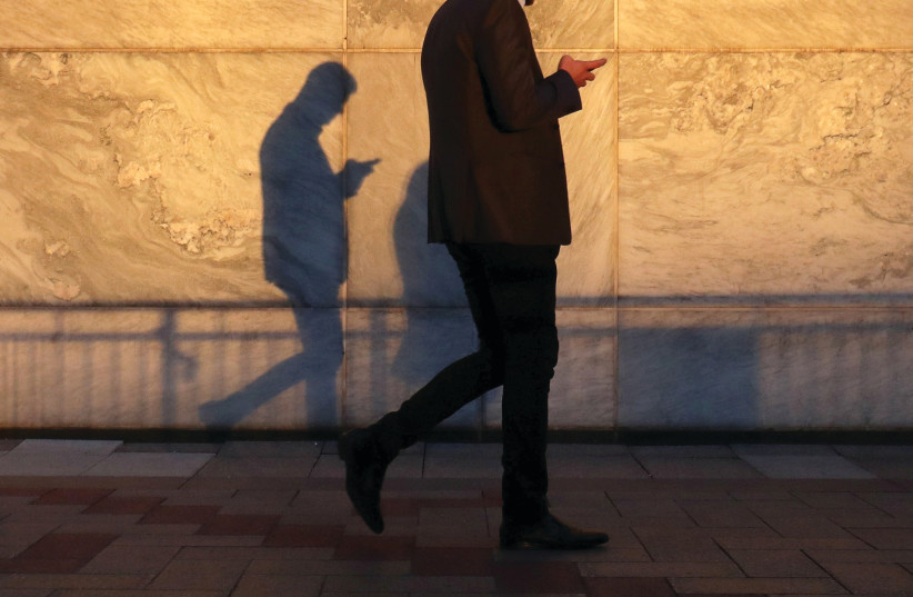 A man reading from a smartphone (photo credit: REUTERS)