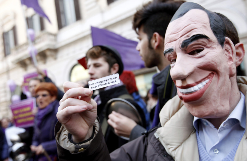 A protestor wearing a mask depicting Italian Prime Minister Silvio Berlusconi holds a paper during a demonstration calling for the resignation of Berlusconi in Rome February 12, 2011.  (photo credit: ALESSIA PIERDOMENICO / REUTERS)
