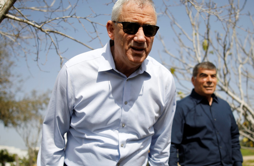 Benny Gantz, head of Blue and White party, leans forward as his party candidate Gabi Ashkenazi stands nearby during a visit to Kibbutz Kfar Aza, outside the northern Gaza Strip, in southern Israel March 13, 2019 (photo credit: AMIR COHEN/REUTERS)