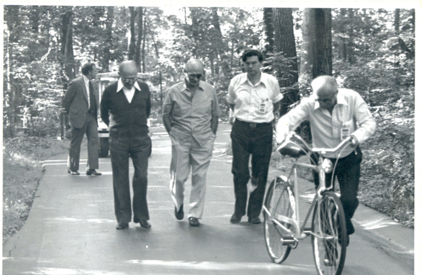 STROLLING IN Camp David, northern Maryland: (left to right) Prime minister Menachem Begin; foreign minister Moshe Dayan; Aharon Barak, then a legal expert with the Israeli delegation and a future president of the Supreme Court; and Yehiel Kadishai (on bicycle), Begin’s longtime aide. (photo credit: MOSHE MILNER / GPO)