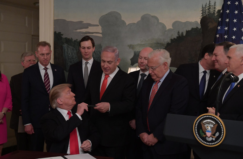 President Donald Trump signs a document acknowledging Israel's sovereignty over the Golan Heights, on March 25, 2019 as Prime Minister Benjamin Netanyahu looks on. (photo credit: AMOS BEN-GERSHOM/GPO)