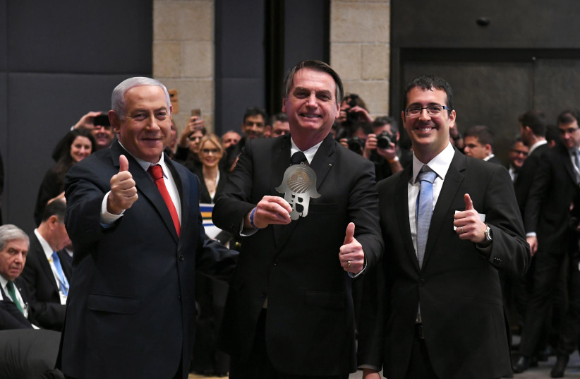 Benjamin Netanyahu (R) and Jair Bolsanaro (C) give a thumbs up at a business forum at Jerusalem's David Citadel Hotel, April 2nd, 2019 (photo credit: AMOS BEN-GERSHOM/GPO)