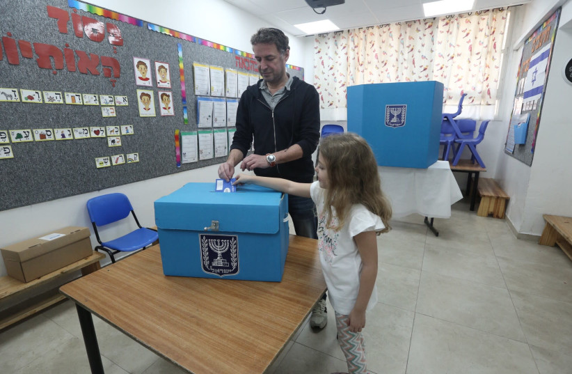 A child helps cast a vote by placing a ballot in a box in Jerusalem's Baka neighborhood, April 9th, 2019 (photo credit: MARC ISRAEL SELLEM/THE JERUSALEM POST)