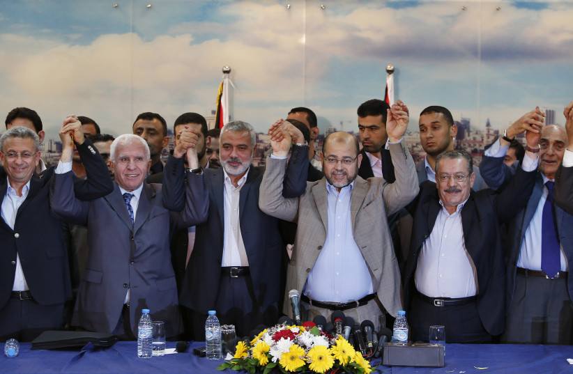 Senior Fatah official Azzam Al-Ahmed (2nd L), head of the Hamas government Ismail Haniyeh (3rd L) and senior Hamas leader Moussa Abu Marzouq (4th L) , hold their hands after announcing a reconciliation agreement in Gaza City April 23, 2014. The Gaza-based Islamist group Hamas and President Mahmoud A (photo credit: SUHAIB SALEM / REUTERS)