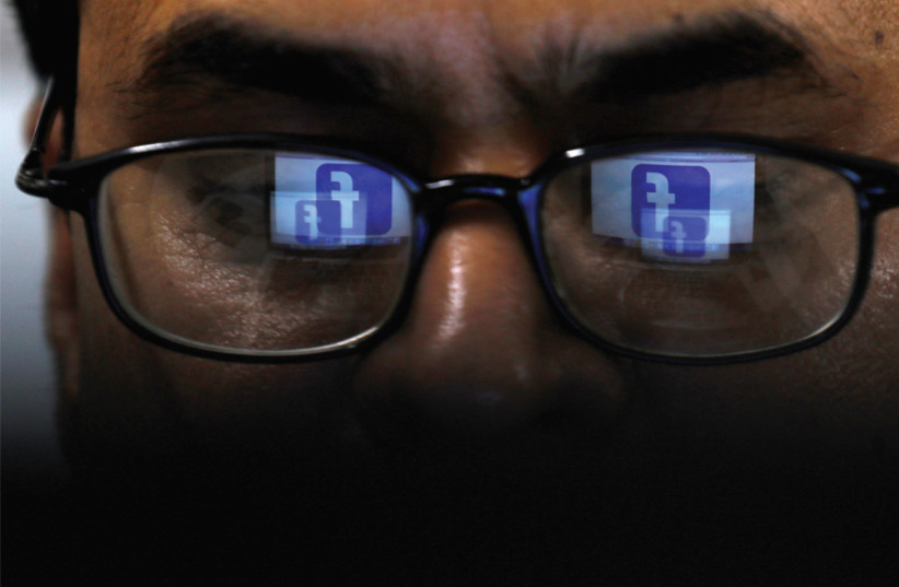 Facebook logo is reflected in glasses in this picture illustration taken April 1, 2019 (photo credit: REUTERS)
