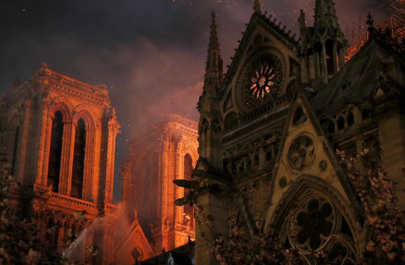 Sparks fill the air as Paris Fire brigade members spray water to extinguish flames as the Notre Dame Cathedral burns in Paris, France, April 15, 2019. (credit: PHILIPPE WOJAZER/REUTERS)