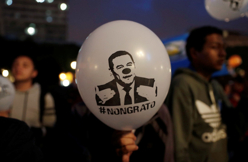 A demonstrator holds a balloon with an image depicting Guatemala's President Jimmy Morales as a clown during a protest against Guatemala's his decision to not renew the mandate of the U.N.-backed anti-graft commission, the International Commission Against Impunity (CICIG), in Guatemala City, Guatema (photo credit: LUIS ECHEVERRIA / REUTERS)