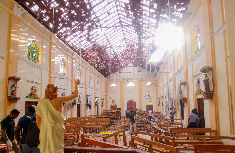 A blood-spattered statue of Jesus Christ is pictured while crime scene officials inspect the site of a bomb blast, as the sun shines through the blown-out roof, inside St Sebastian's Church in Negombo, Sri Lanka April 21, 2019 (photo credit: REUTERS)