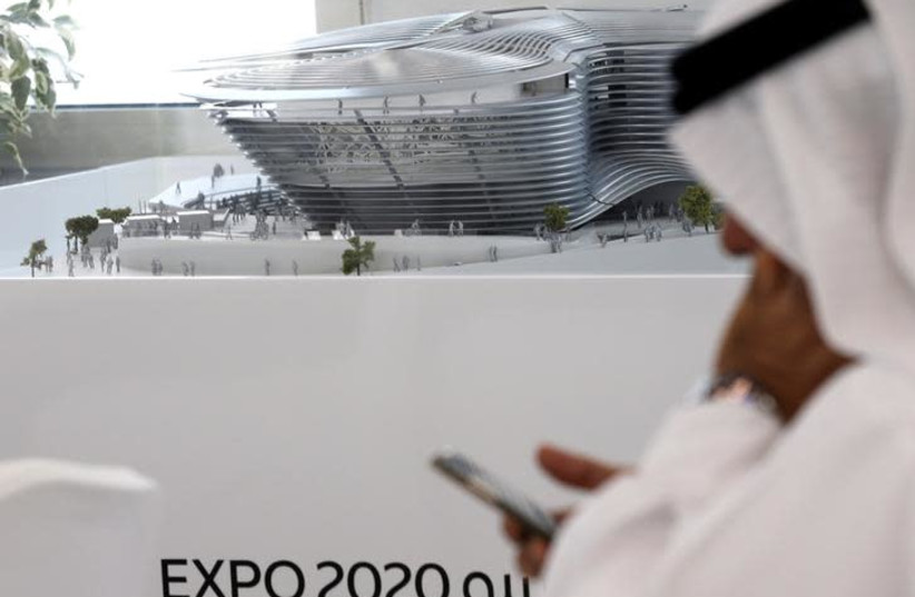 A man uses his mobile device next to a model of the Expo 2020 project in Dubai, United Arab Emirates (photo credit: REUTERS/STRINGER)