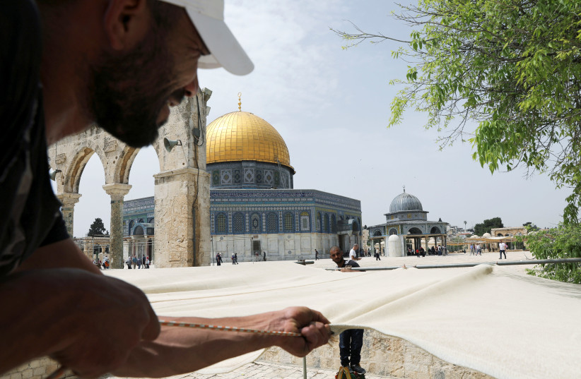 Workers put up canvases to provide shade for worshippers on the sacred compound known to Muslims as the Noble Sanctuary and to Jews as the Temple Mount, in preparation for the holy Muslim month of Ramadan, in Jerusalem's Old City April 30, 2019.  (photo credit: AMMAR AWAD / REUTERS)