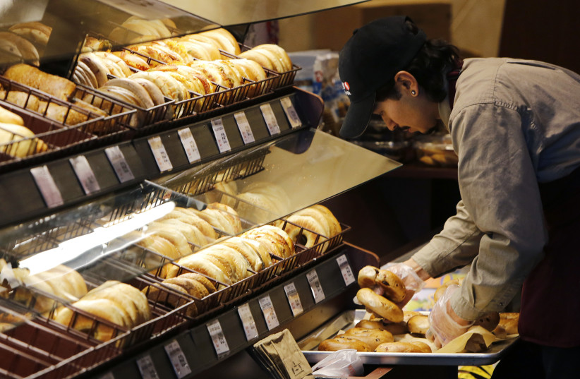 A baker puts out fresh bagels at the store, 2015. (credit: REUTERS/GARY CAMERON)
