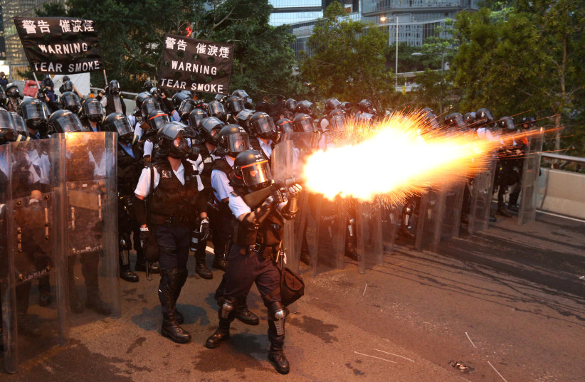 Police officers fire a tear gas during a demonstration against a proposed extradition bill in Hong Kong, China June 12, 2019. (photo credit: REUTERS/ATHIT PERAWONGMETHA)