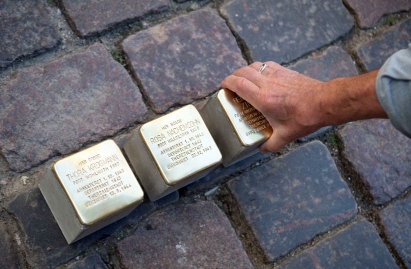 German artist Gunter Demnig puts three 'Snublesten', or Stolpersteine, in front of the Synagogue in Copenhagen, Denmark, June 17, 2019. A stumbling block is a memorial stone laid in the pavement next to houses where victims of Nazism had their homes (photo credit: REUTERS)