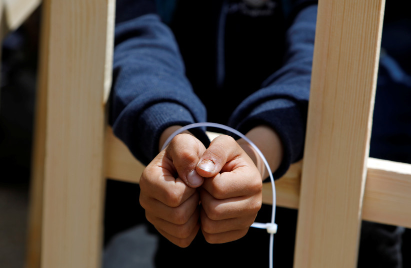A boy playing the role of a prisoner has his hands tied during a rally marking Palestinian Prisoners' Day April 17, 2019. (photo credit: RANEEN SAWAFTA/ REUTERS)