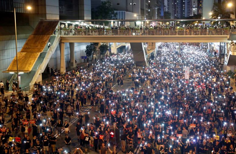 Anti-extradition bill protesters use the flashlights from their phones as they march during the anniversary of Hong Kong's handover to China in Hong Kong (photo credit: TYRONE SIU/ REUTERS)