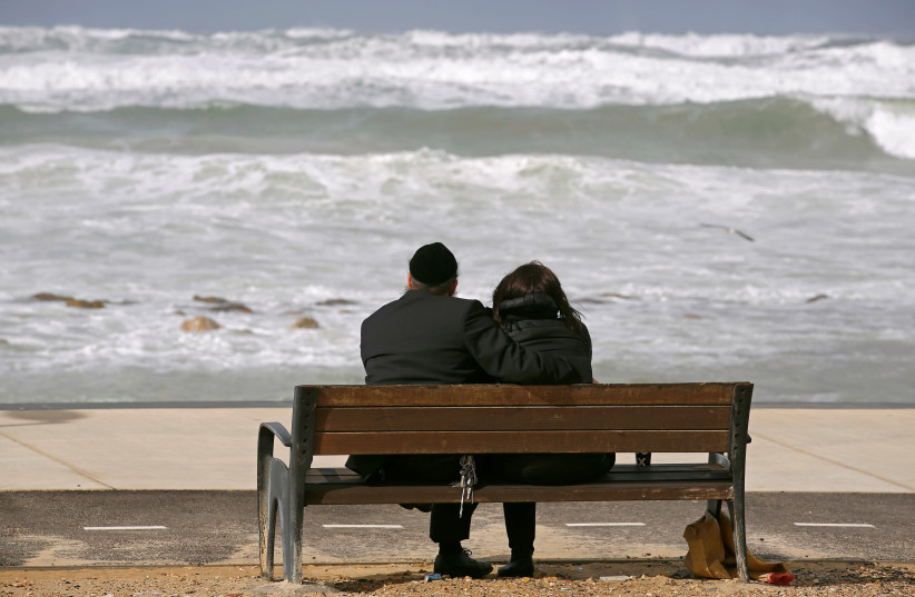An ultra-Orthodox couple watches the sea during a storm in the Mediterranean coast of the city of Ashkelon, Israel January 19, 2018. (credit: AMIR COHEN/REUTERS)