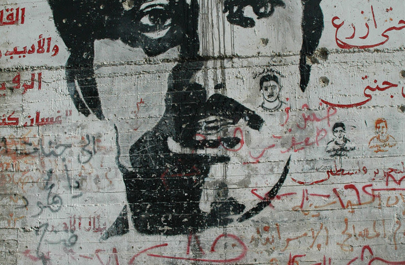 A graffiti image of PFLP terrorist Ghassan Kanafani on the security barrier in the West Bank (credit: WIKIMEDIA COMMONS/JUSTIN MCINTOSH)