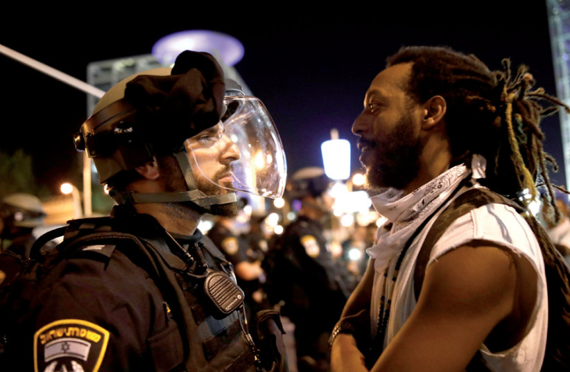 A protester confronts a policeman during a demonstration in Tel Aviv on July 2 over the shooting death of 19-year-old Ethiopian- Israeli Solomon Tekah (photo credit: CORINNA KERN/REUTERS)