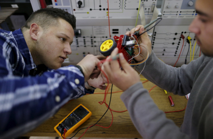 Palestinian students check a small electronic car that they control by an electronic glove they developed, at Birzeit University in the West Bank town of Birzeit January 21, 2016 (photo credit: AMMAR AWAD / REUTERS)
