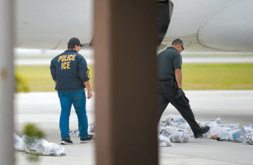 LAW ENFORCEMENT officials look over bags of belongings to be loaded onto a chartered plane with migrants in US Immigration and Customs Enforcement (ICE) custody, before departure from Brownsville South Padre International Airport in Texas on May 18. (photo credit: LOREN ELLIOTT/REUTERS)