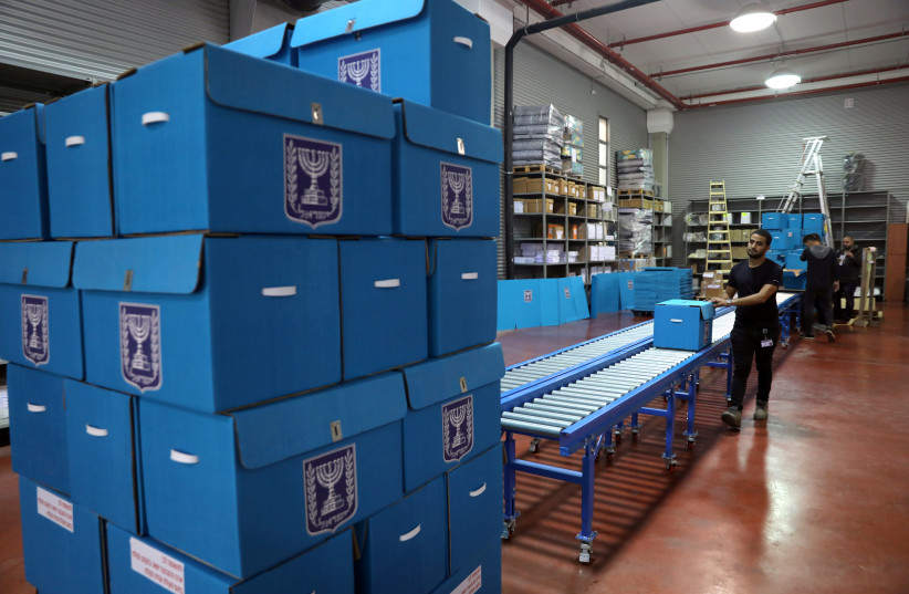 People sort ballot boxes as part of preparations for the upcoming Israeli election, during a briefing for members of the media at the Israel Central Election Committee Logistics Center in Shoham, Israel (credit: REUTERS)