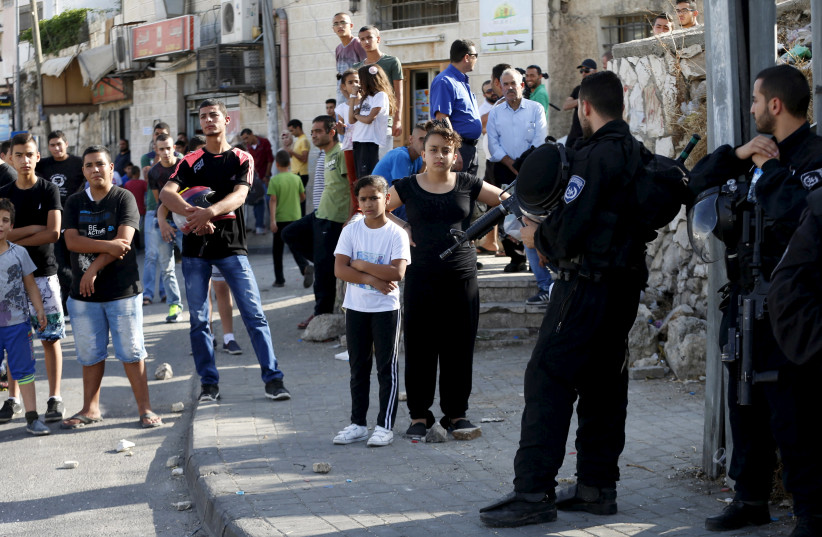 Palestinians look on as Israeli police set up a checkpoint in the Arab east Jerusalem neighbourhood of Ras al-Amud October 14, 2015 (photo credit: AMMAR AWAD/REUTERS)