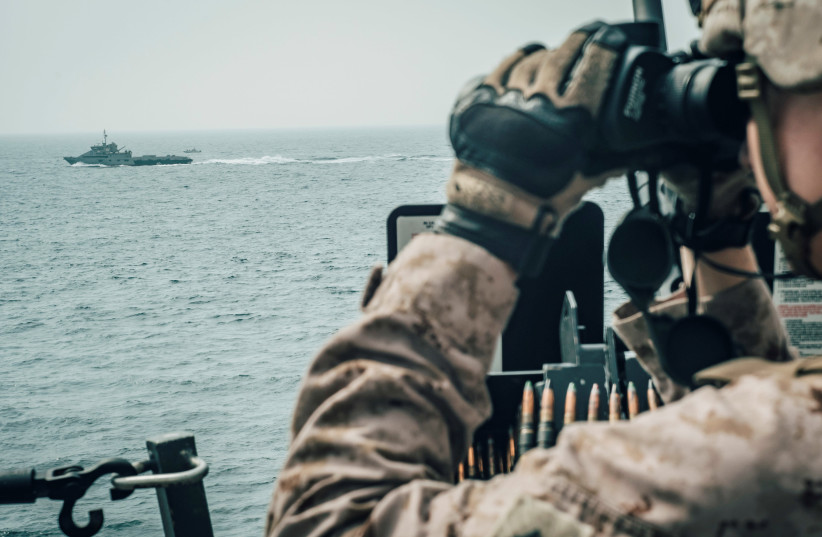 A U.S. Marine observes an Iranian fast attack craft from USS John P. Murtha during a Strait of Hormuz transit, Arabian Sea off Oman, in this picture released by U.S. Navy on July 18, 2019 (photo credit: REUTERS)