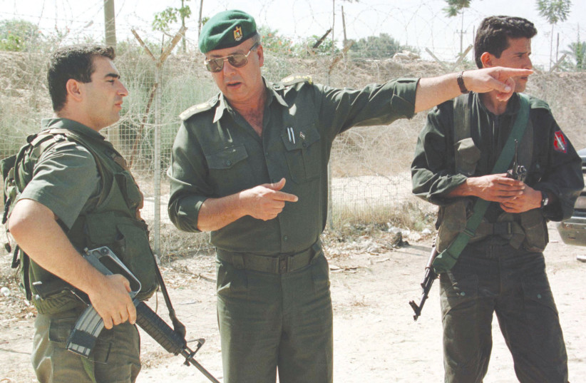 A PALESTINIAN POLICE officer gestures as he speaks with an IDF soldier during a joint patrol in 1998.  (photo credit: REUTERS)