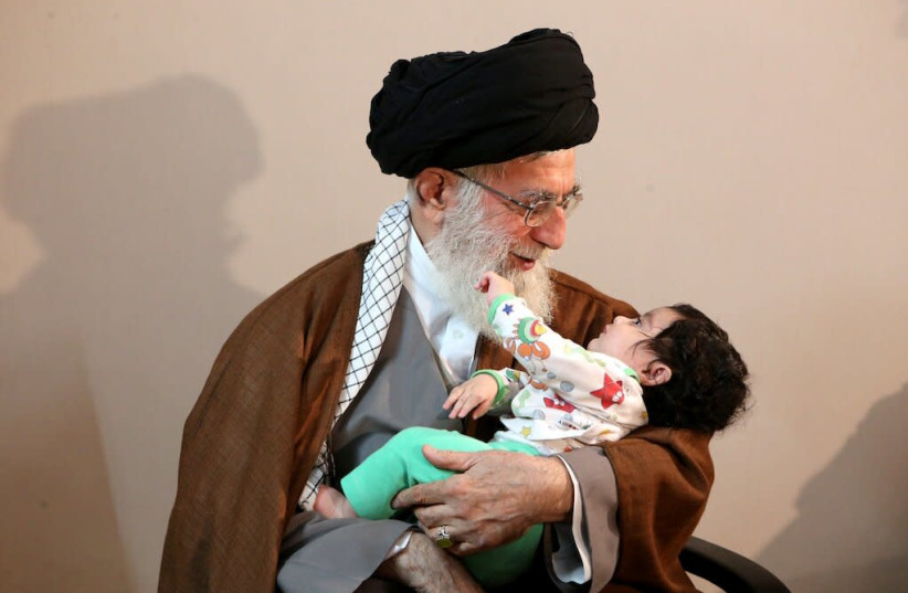 Iran's Supreme Leader Ayatollah Ali Khamenei smiles at a baby (photo credit: KHAMENEI.IR)