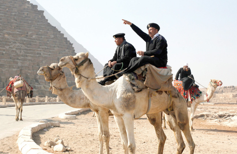 A POLICE officer atop a camel talks to workers at the Giza pyramids, south of Cairo. (photo credit: ASMAA WAGUIH/REUTERS)